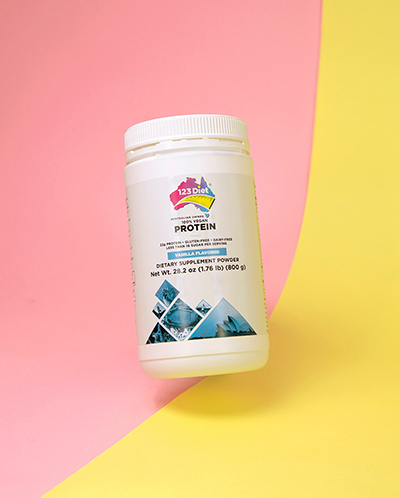 Our new Vegan Protein, falling on a pink and yellow background